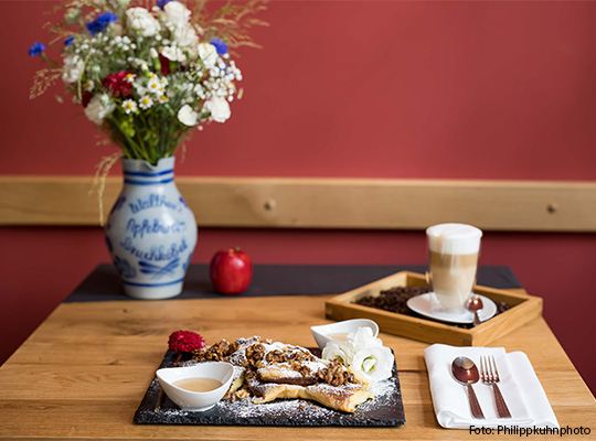 Gedeckter hölzerner Tisch mit Dessert und einem Kaffee darauf