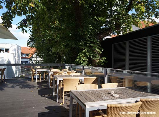 Außenbereich des Parks, in form einer Holzveranda mit Bar-Hockern und Tischen