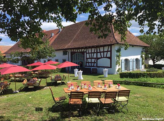 Außenansicht der Wiese vor dem Hof mit Tischen auf der Wiese