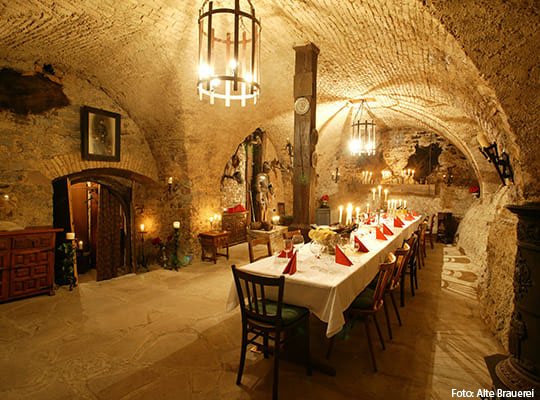 Festlich eingerichtete Halle mit Kronleuchtern an der Decke in einem Gewölbekeller mit Tisch